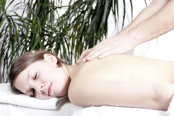 A woman getting her back massage done by someone.