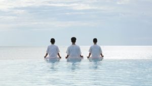 Three people sitting in the water of a body of water