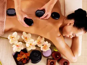 A woman is getting her back turned to get some hot stone massage.