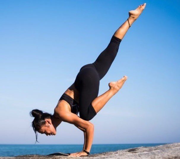 A woman doing a handstand on top of her head.