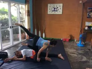 Two people are doing a yoga pose on the floor.